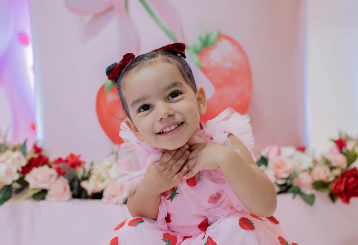 Menina sorrindo em festa de aniversário tema morangos em Londrina