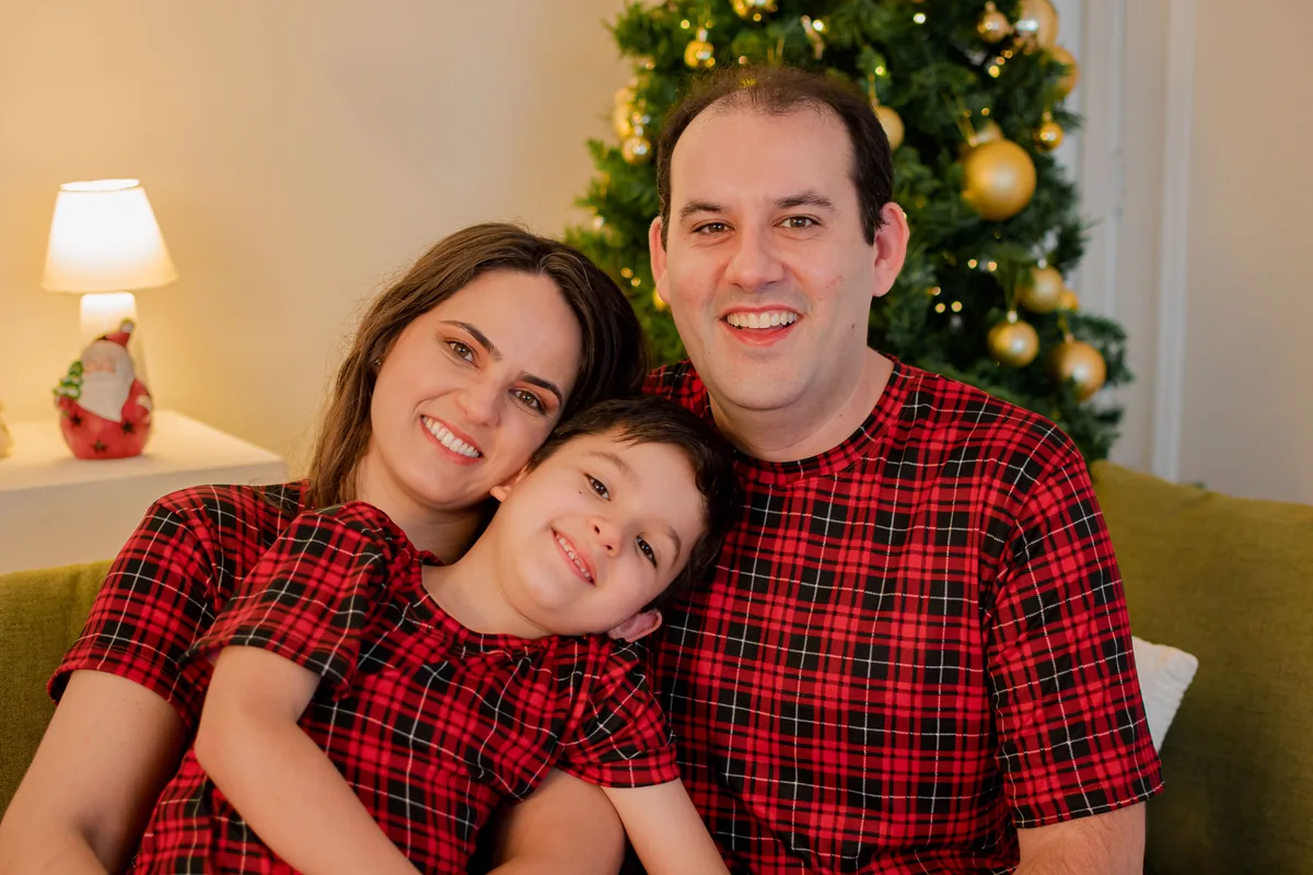 Família de pijama xadrez vermelho com árvore de Natal ao fundo em Londrina