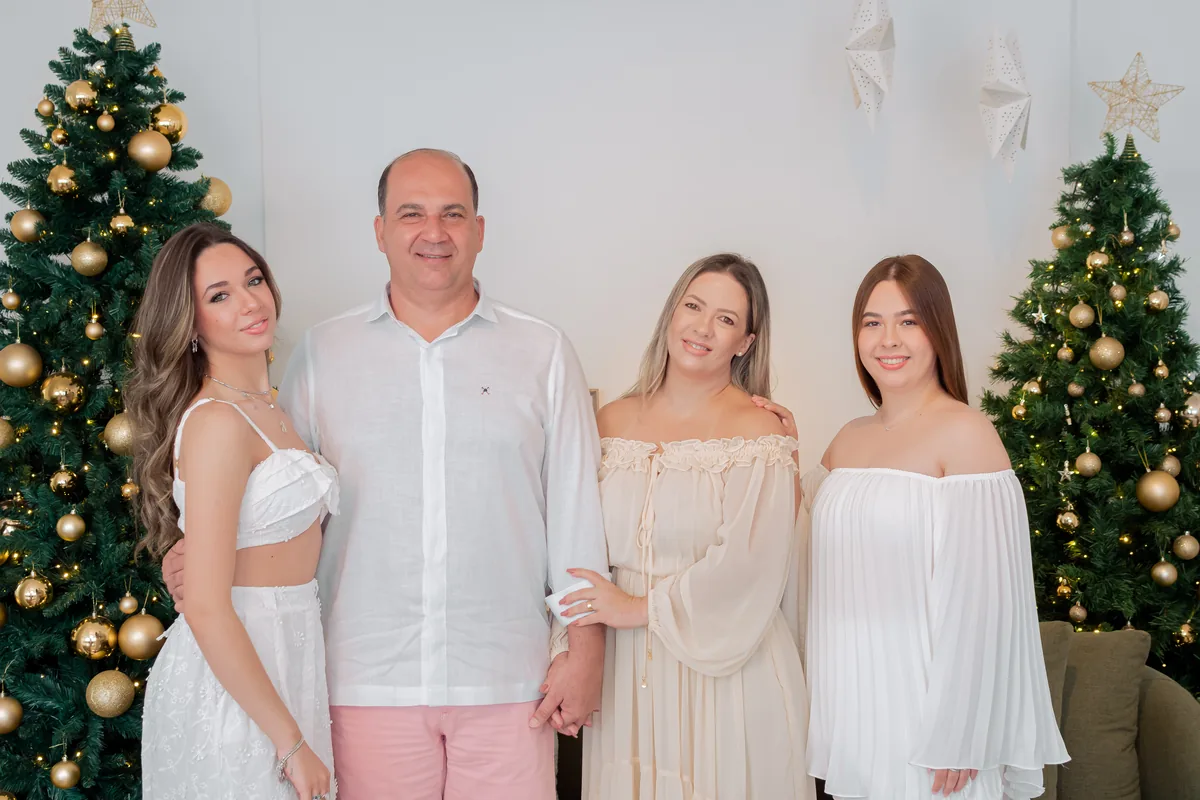 Família com filhas adultas em ensaio de Natal com cenário branco e dourado em Londrina